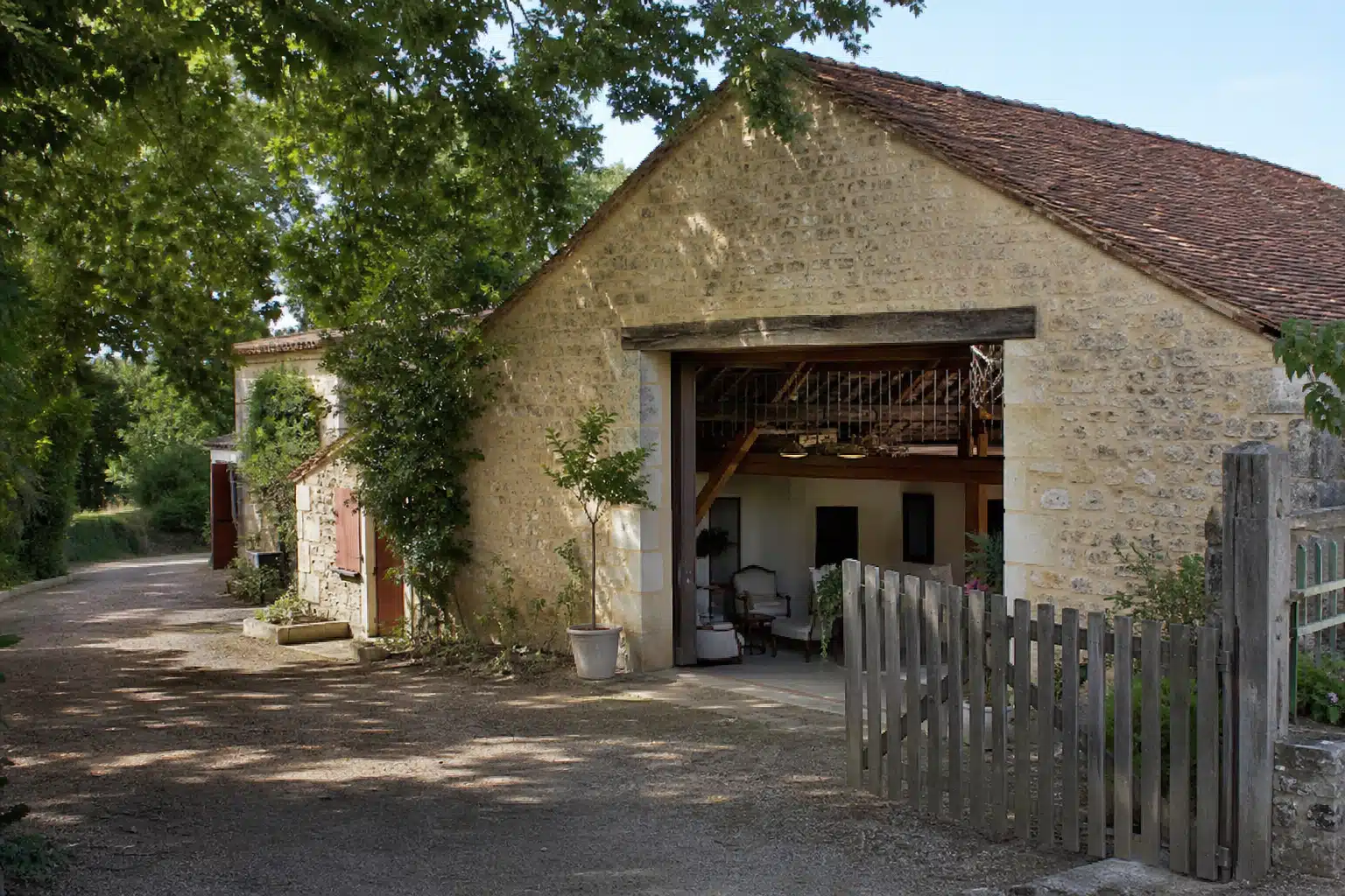 Garage ouvert dans une bâtisse en pierre ombragée